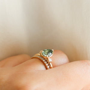 Pear cut green sapphire engagement ring with half eternity diamond band on hand