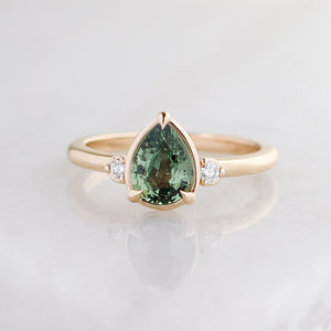 Pear cut green sapphire engagement ring front view indirect light