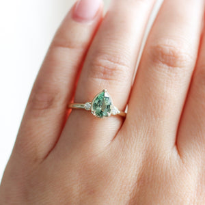 Pear cut green sapphire engagement ring on hand