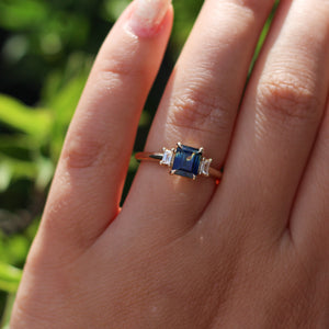 Emerald cut blue sapphire ring on hand in the sun