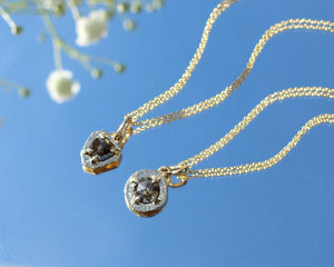 Shield Rustic Diamond Pendants with chains on a mirror in light with flowers