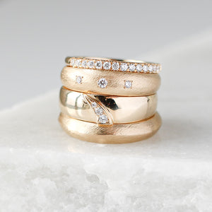 Shooting Star Diamond Wide Band stacked with 3 diamond gold wide and stacking bands on marble quarter view